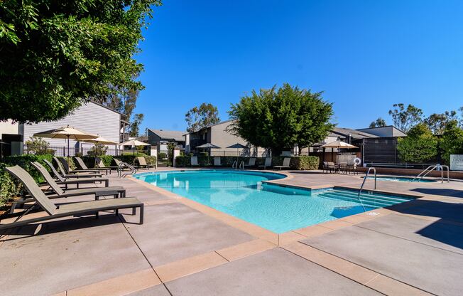 A swimming pool surrounded by lounge chairs and trees.