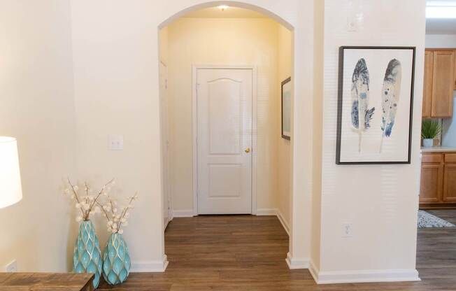 A hallway with a white door and a framed picture on the wall.