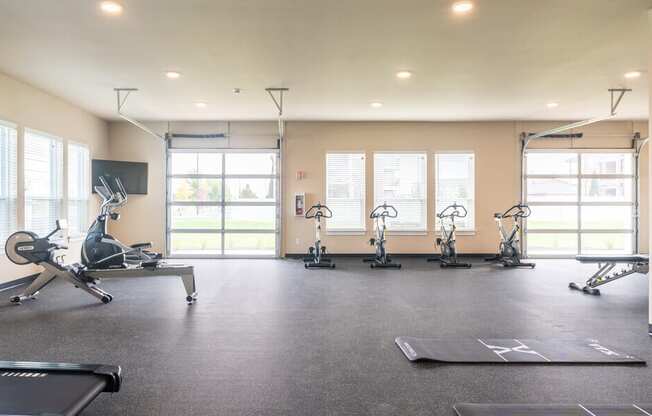 a gym with treadmills and weights on the floor and windows