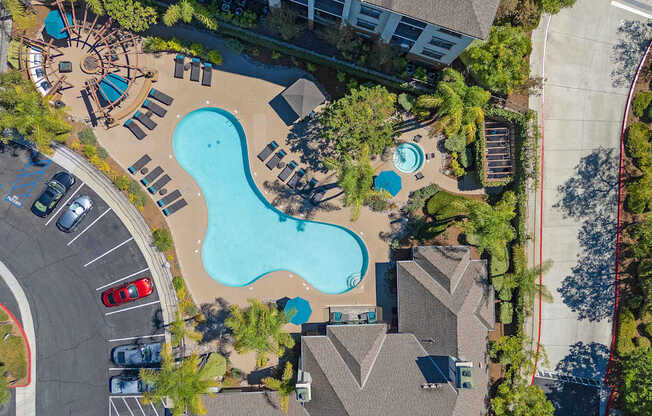 An aerial view of a swimming pool surrounded by trees and buildings.