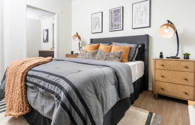 A bedroom with a large bed, a nightstand, and a lamp.