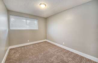 A room with a carpeted floor and a window with blinds.