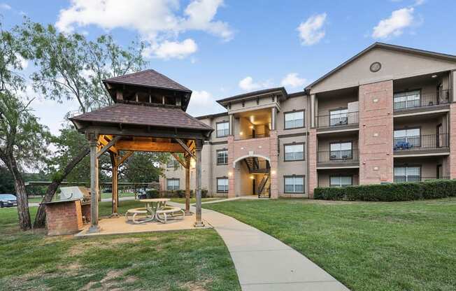 a pavilion with a picnic table in front of an apartment building
