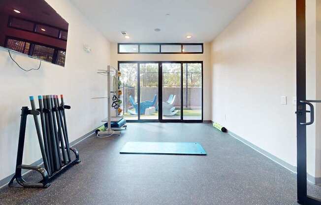 A gym with a blue mat and a row of dumbbells.