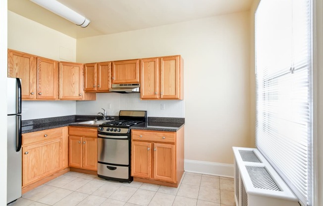 kitchen with stainless steel appliances, wood cabinetry and large window at norwood apartments in washington dc