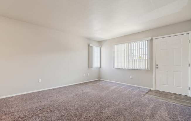 an empty living room with carpet and a white door