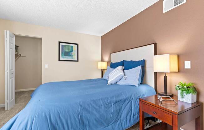 A bedroom with a blue bedspread and a white pillow.