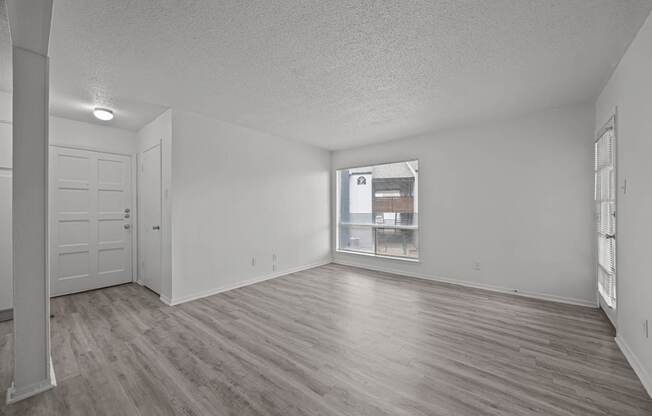 A spacious room with wooden flooring and white walls.