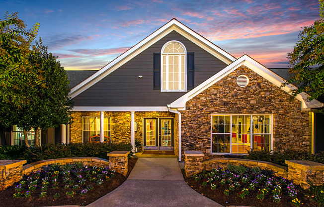 the exterior of a home at sunset with a driveway and a stone facade