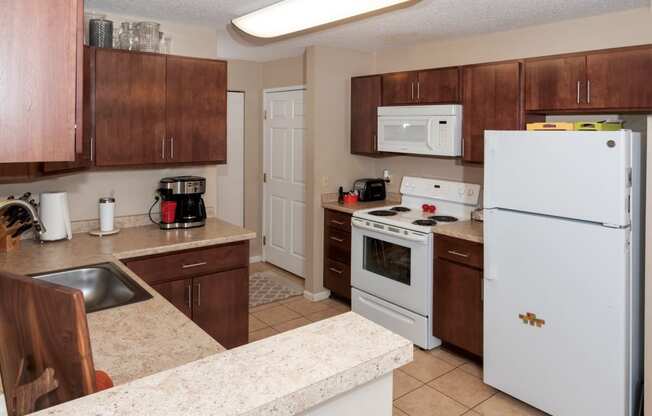 a kitchen with white appliances and counters and wooden cabinets