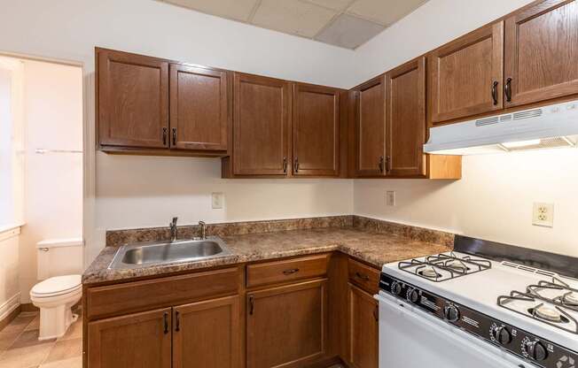 A kitchen with a white stove top oven and brown cabinets.
