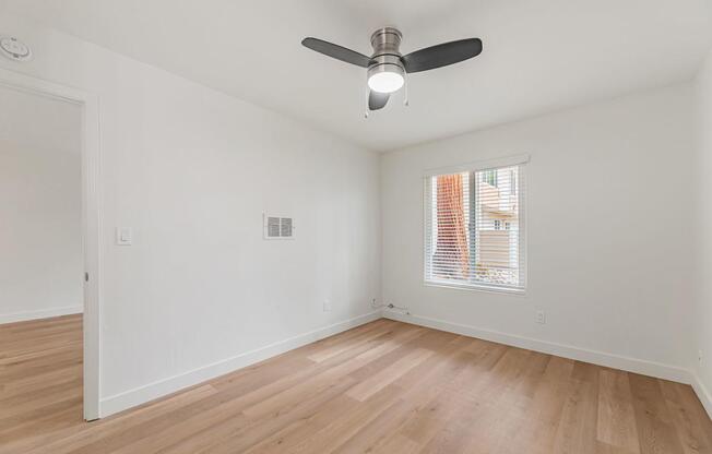 A room with a ceiling fan and a window with blinds.