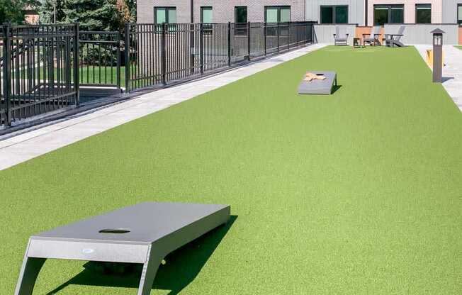 a turf green space with a set of cornhole boards