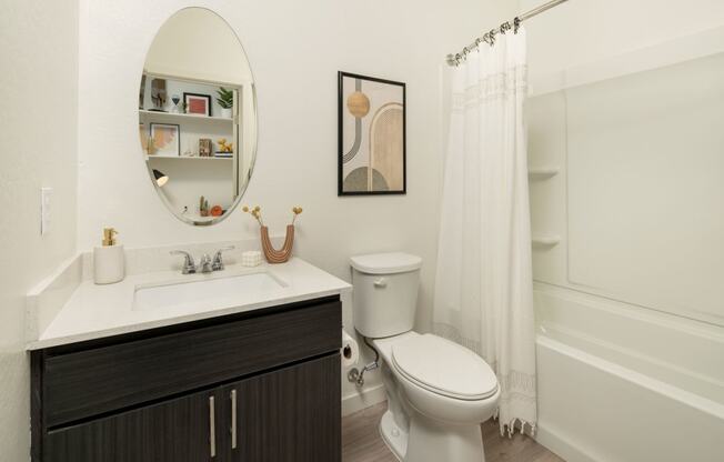 a bathroom with a white sink and toilet next to a white bathtub with a shower curtain