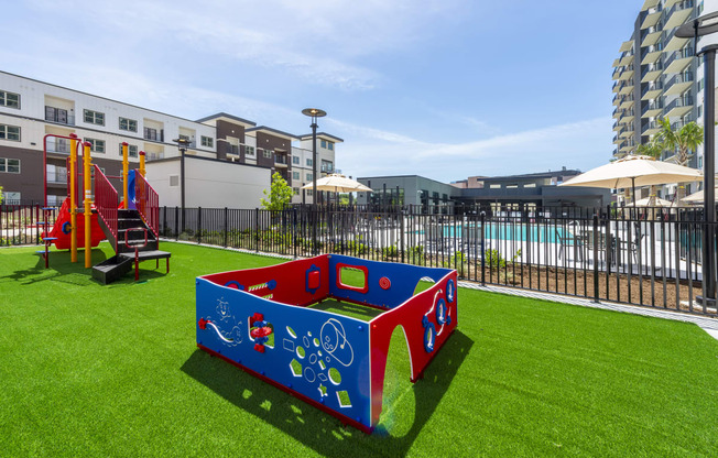 a childrens play area in a yard with a pool and buildings