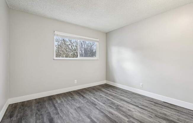 A room with a window and a grey floor.