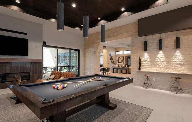 A pool table is in the middle of a room with a fireplace and a TV.