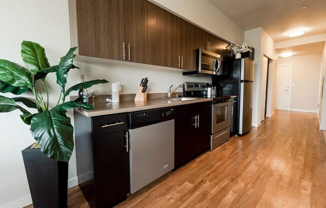 A kitchen with dark wood cabinets and stainless steel appliances. at The Platform, Kent, WA, 98032