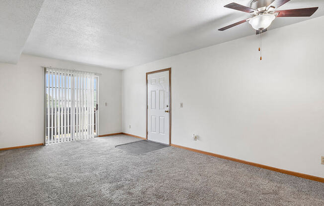 a bedroom with a ceiling fan and a door to a balcony