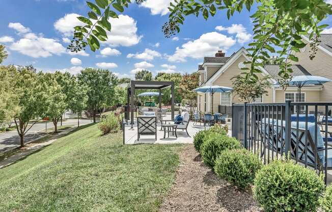 a yard with a patio with tables and chairs and a fence