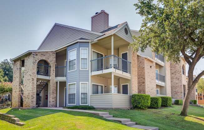 the outlook of an apartment building with a lawn and tree