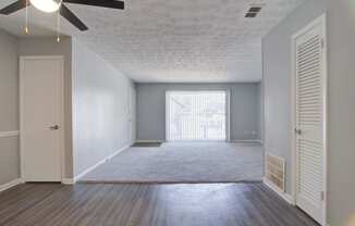 an empty living room with a ceiling fan