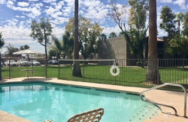 a swimming pool with chairs next to a fence