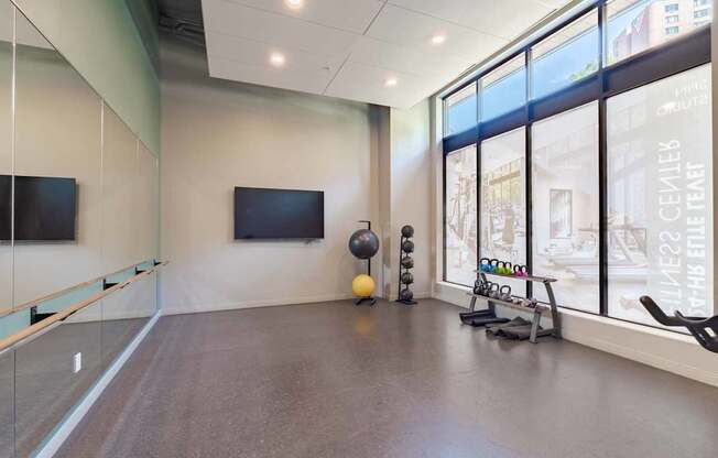 A spacious room with a television, exercise equipment, and large windows.