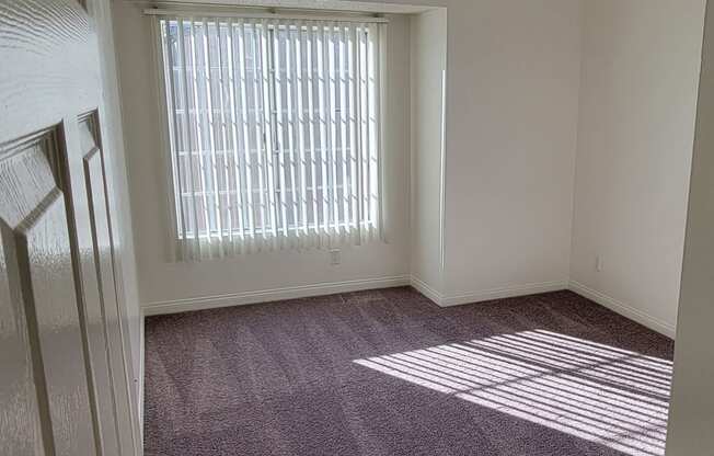 Carpeted bedroom with large window at Northwood Apartments in Upland, California.