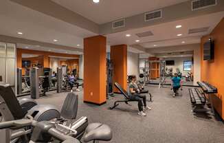 A gym with people working out and various exercise equipment.