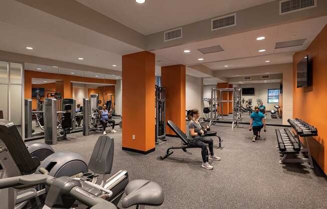 A gym with people working out and various exercise equipment.