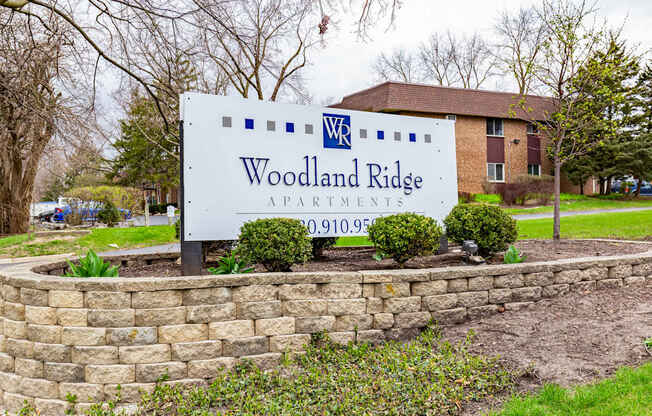 A sign for Woodland Ridge Apartments stands in front of a brick building.