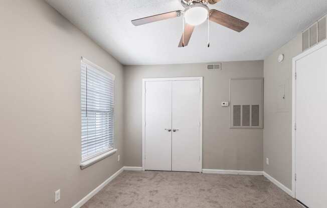 an empty bedroom with a ceiling fan and a closet