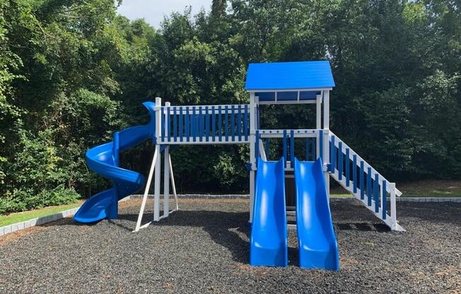 a playground with a blue slide and a swing set
