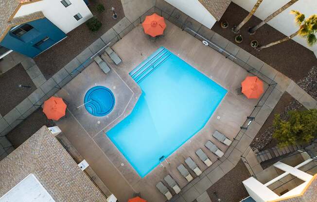 A swimming pool surrounded by orange umbrellas and a tiled floor.