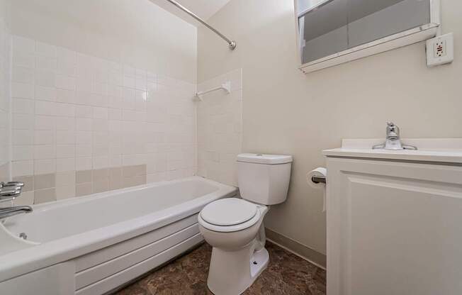 A white toilet sits next to a bathtub in a bathroom.