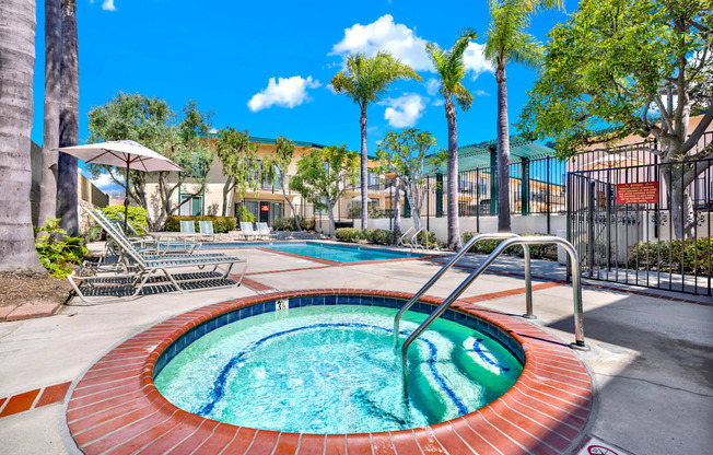 a jacuzzi pool with palm trees and a building in the background at Camino de Oro Apartments, Torrance, California