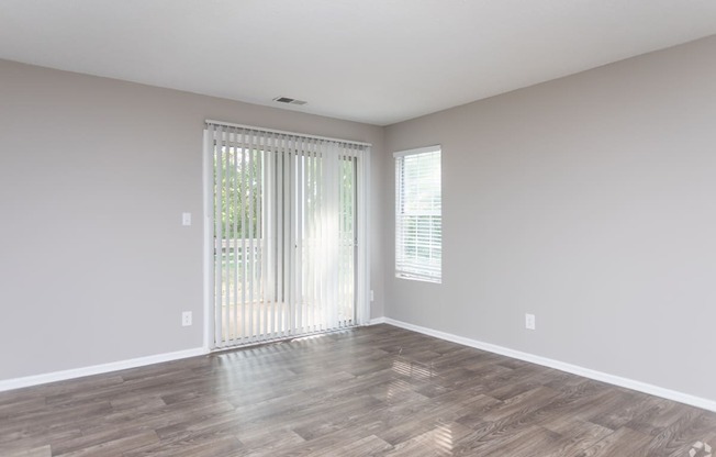 an empty living room with white walls and a sliding glass door