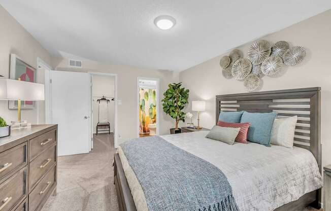 A bedroom with a bed, dresser, and a plant.