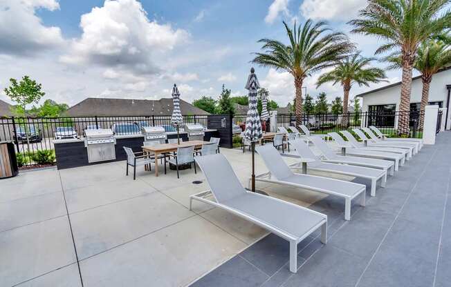 A row of white lounge chairs are arranged on a patio.