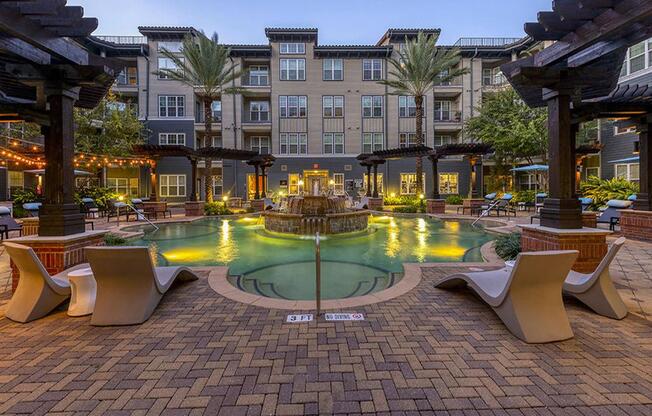 a fountain in the middle of a courtyard with chairs and a pool