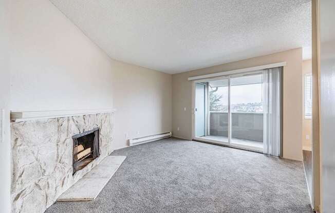 Living room featuring a stone-style fireplace, neutral paint, and grey carpet in a 2 Bed 1 Bath at Peak 88 in Renton, WA.