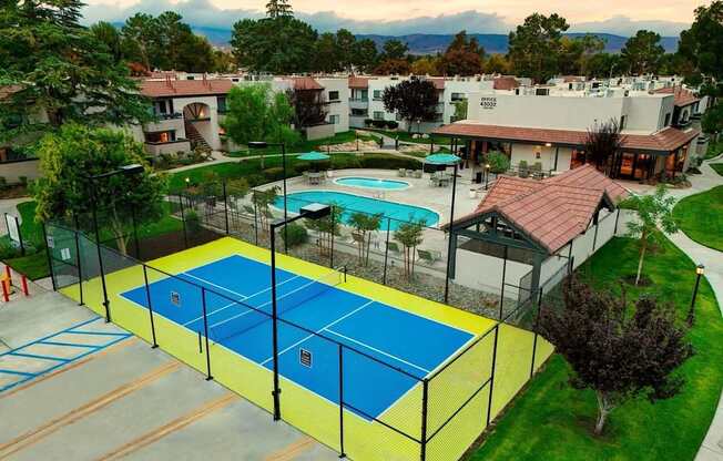 A tennis court is surrounded by a fence and a pool.