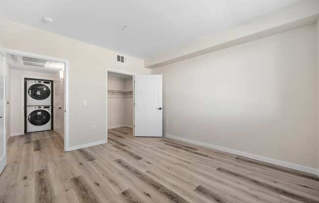 a living room with white walls and wood floors and a washer and dryer