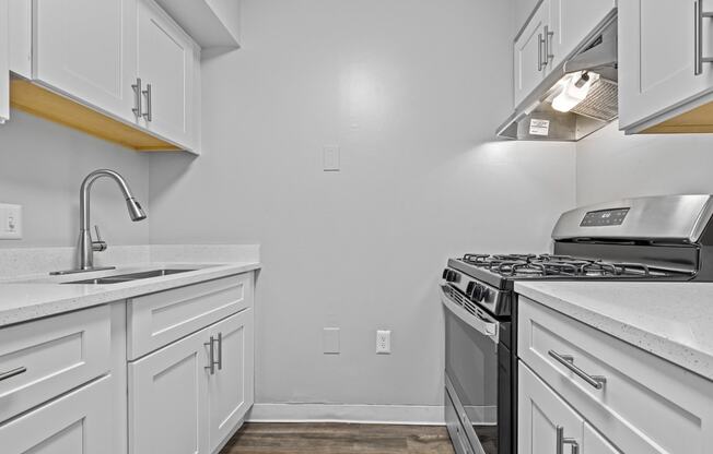 the renovated kitchen of an apartment with white cabinets and stainless steel appliances