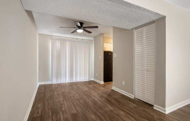 an empty living room with a ceiling fan and closet