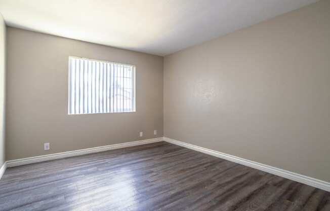 A room with wooden flooring and a window with blinds.