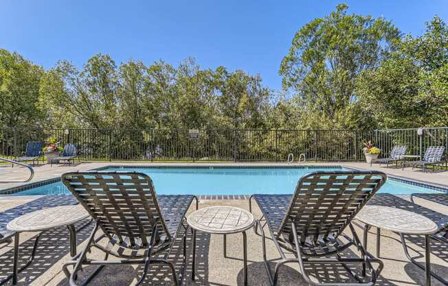 a swimming pool with chairs and tables next to it