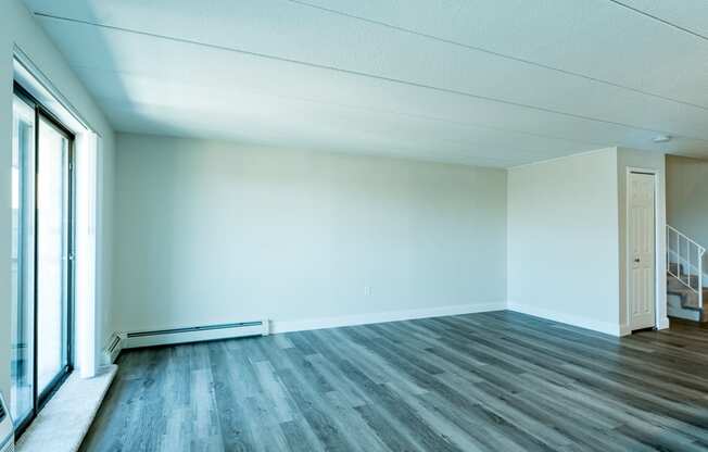 an empty room with a large window and hardwood floors