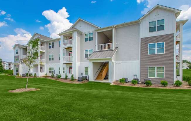 A large white apartment building with a green lawn in front.